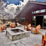 A stone patio with wooden Adirondack chairs