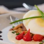 A plated gourmet poached egg, garnished with chives