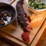 Cooked meat, a dollop of red sauce, and a bowl of Brussels sprouts