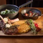 Cooked meat with herbs, a potato cake, and sautéed vegetables