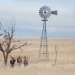 Group near windmill in prairie
