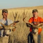 Two hunters with trophy deer heads.