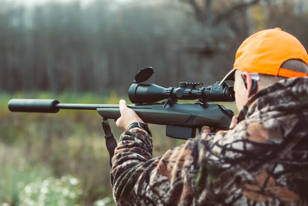 Hunter aiming rifle in camouflage outfit